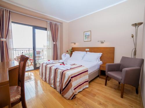 ein Hotelzimmer mit einem Bett, einem Stuhl und einem Fenster in der Unterkunft Hotel Petrovac in Petrovac na Moru