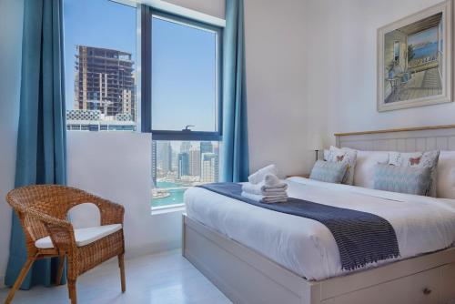 a bedroom with a bed and a chair and a window at Maison Privee - Stunning Apartment with Dubai Marina View in Dubai