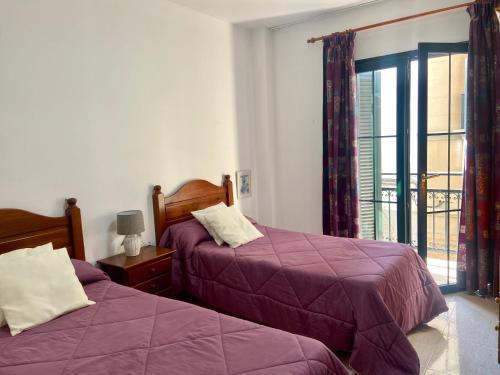 - une chambre avec 2 lits avec des draps violets et une fenêtre dans l'établissement Casa Inma. Espacio y confort en Arrecife, à Arrecife