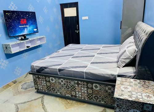 a bedroom with a bed and a tv on a wall at Smart Stays - MMMUT College - GKP Airport in Gorakhpur
