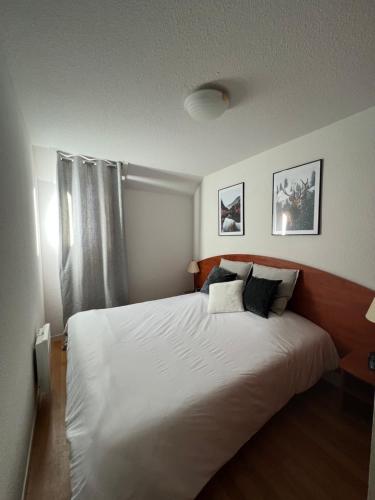 une chambre avec un grand lit blanc et une fenêtre dans l'établissement La Mongie magnifique Appart 7 pers vue pistes, piscine, wifi, salle de sport, à La Mongie