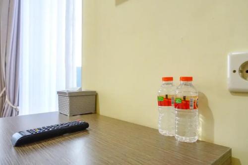 dos botellas de agua y un mando a distancia en una mesa en De Malang Sweet Homestay Syariah Mitra RedDoorz en Malang