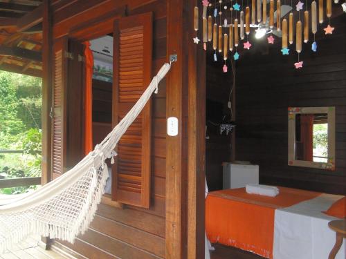 a porch of a wooden house with a hammock at Pousada Riacho Dos Cambucas in Abraão