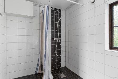 y baño con ducha y azulejos blancos. en First Camp Gränna - Vättern en Gränna