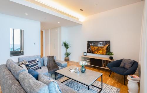 een woonkamer met een bank en een tv bij Maison Privee - Stunning Sea Views on Dubai's New Luxury Island in Dubai