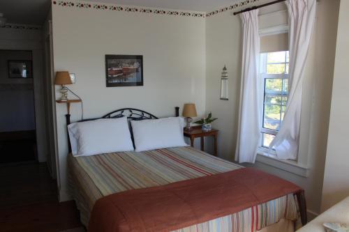 a bedroom with a bed and a window at Compass Rose Heritage Inn in North Head
