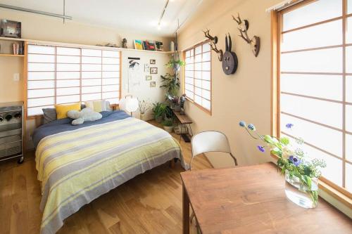 1 dormitorio con cama, mesa y ventanas en PDO INN Coffee & Open-air bath on the roof, en Tokio