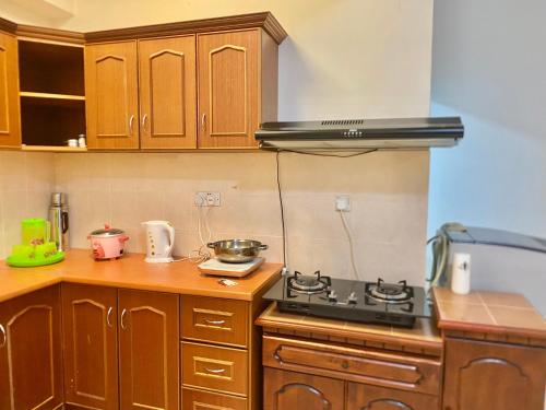 a kitchen with wooden cabinets and a stove top oven at Homestay Legacy Kamariah Ahmad,Lumut in Lumut