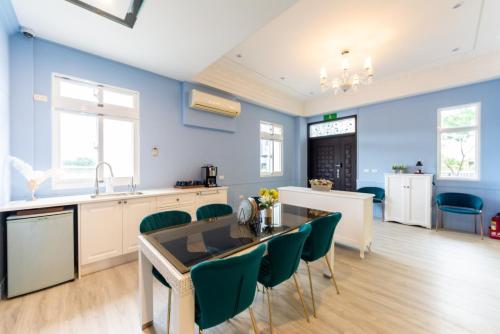 a kitchen with blue walls and a table with green chairs at Romatic Venice Homestay in Luodong