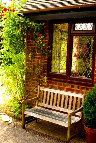 a wooden bench in front of a brick building with a window at Tovey Lodge in Hassocks