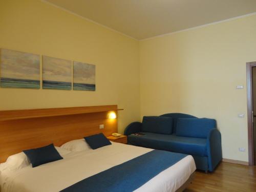 a bedroom with a bed and a blue chair at Hotel Sacro Cuore in Perugia