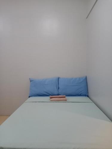 a white bed with a blue pillow on it at Sunvida Cebu in Cebu City