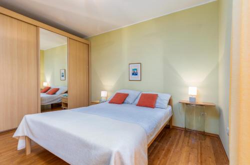 ein Schlafzimmer mit einem großen weißen Bett mit zwei orangenen Kissen in der Unterkunft Apartment Luana A1 in Fažana