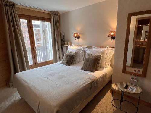 a bedroom with a bed with white sheets and a window at Everest Hotel in Val dʼIsère