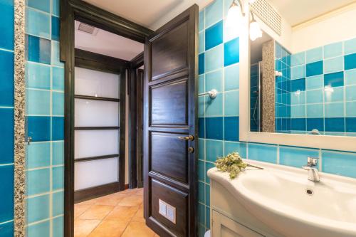 a bathroom with blue tiles and a sink and a mirror at Casa il grande Carrubo in Santa Maria Navarrese