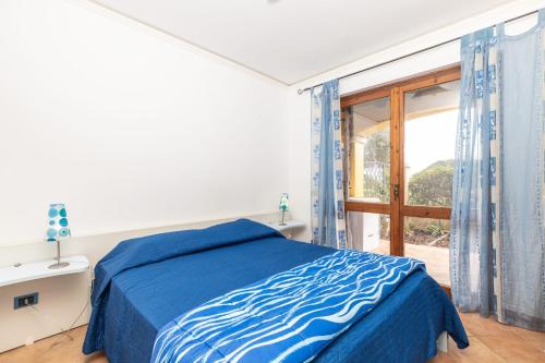 a bedroom with a blue bed and a large window at Casa il grande Carrubo in Santa Maria Navarrese