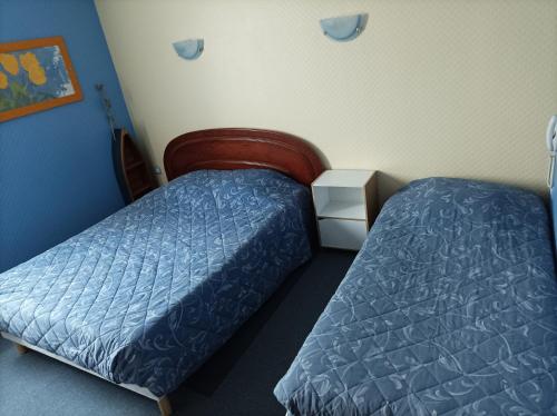two beds in a room with blue walls and blue sheets at La Croisière in Louvetot