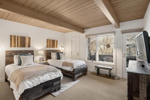 a bedroom with two beds and a tv and a window at Standard Three Bedroom - Aspen Alps #406 in Aspen