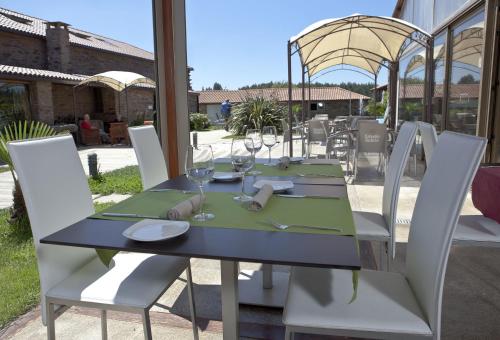 a dining room table with chairs and umbrellas at Albergue Turistico Salceda in Salceda