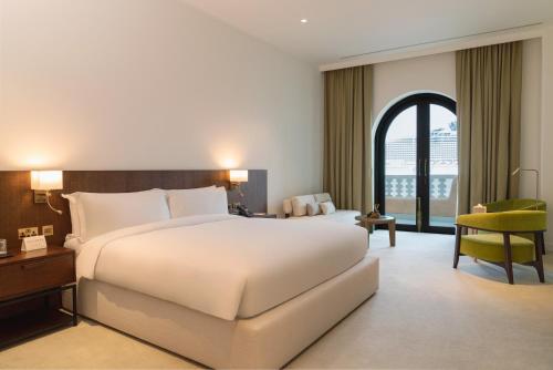 Mina Hotel and Residences في الدوحة: غرفة فندق بسرير ابيض كبير ونافذة