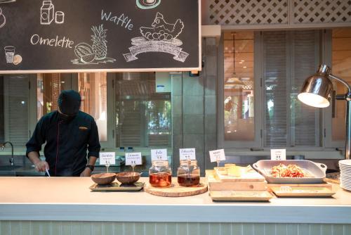 a man standing in front of a counter with food at Khaolak Merlin Resort in Khao Lak