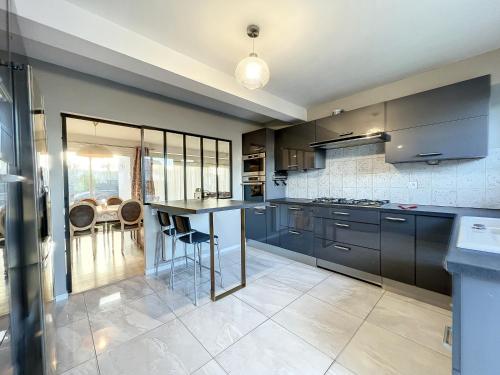 une cuisine avec des armoires noires et une table avec des chaises dans l'établissement VILLA BELLA VISTA - Proche Rennes - Billard - Baby-foot, à Liffré