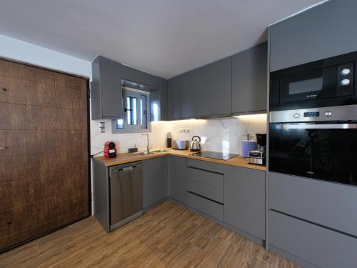 a kitchen with gray cabinets and a black appliances at Old olive tree cottage in Áyioi Apóstoloi