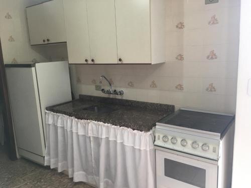 uma cozinha com um lavatório e um frigorífico branco em Campos do Jordão em Campos do Jordão