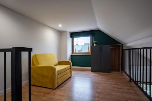 a living room with a yellow chair and a window at Rajskie Uroczysko Apartamenty Jacuzzi Sauna in Rajskie Sakowczyk