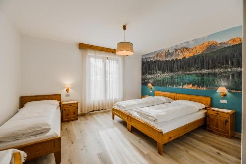 two beds in a room with a painting on the wall at Hotel Garnì Rosengarten in Pera