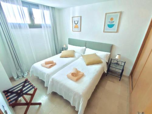 sypialnia z dużym białym łóżkiem z 2 ręcznikami w obiekcie Pearl Apartment Corralejo w Corralejo