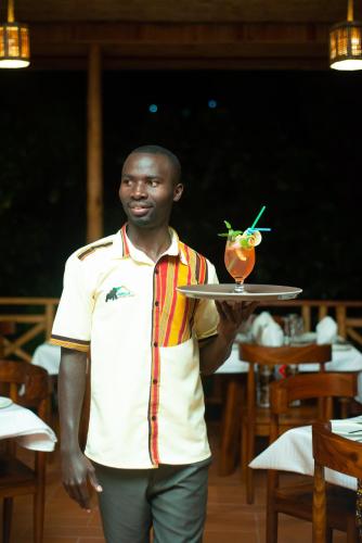 a man holding a tray with a drink on it at Gorilla Leisure Lodge in Kisoro