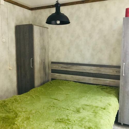 una camera con un letto con una coperta verde di Квартира в стиле лофт a Karagandy