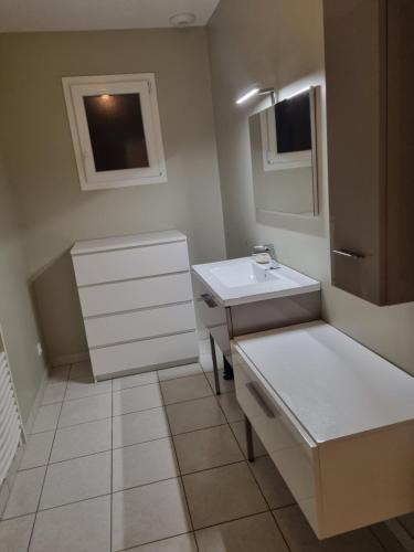 La salle de bains blanche est pourvue d'un lavabo et d'un miroir. dans l'établissement Au cocon de Lin, au Neubourg