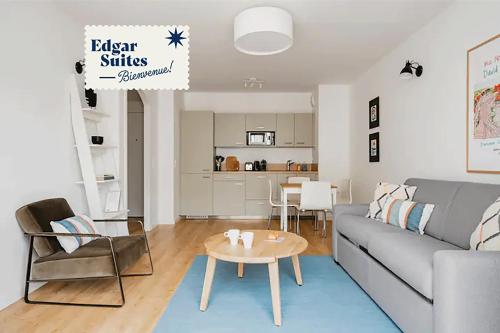 a living room with a gray couch and a table at Edgar Suites Levallois – Jules Verne in Levallois-Perret