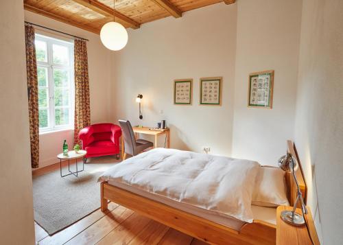 a bedroom with a bed and a desk and a red chair at Hotel Cramer Bed & Breakfast in Werlte