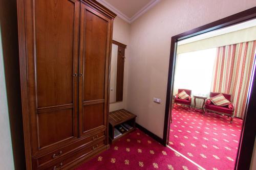 a room with a large wooden cabinet and a room with a mirror at Grand Tien Shan Hotel in Almaty