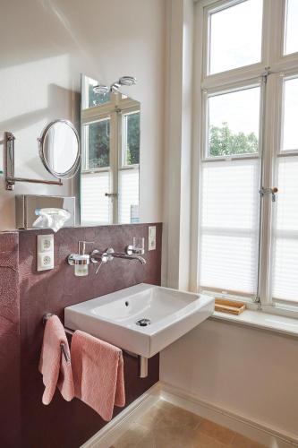 a bathroom with a sink and a mirror and windows at Hotel Cramer Bed & Breakfast in Werlte