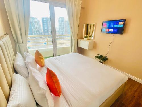 ein Schlafzimmer mit einem Bett mit Kissen und einem Fenster in der Unterkunft Manchester Galaxy - 2BR Apartment in Dubai Marina in Dubai