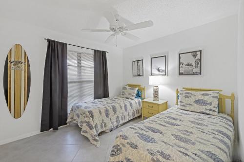a bedroom with two beds and a surfboard on the wall at Inviting condo with pool just a steps from the beach in Marco Island