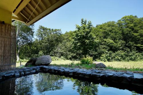 a pool of water with rocks and trees in the background at Hotel Jogakura in Aomori