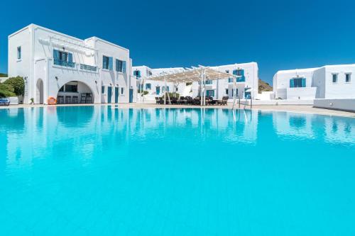 ein Pool mit blauem Wasser vor weißen Gebäuden in der Unterkunft Castellano Village in Maltezana