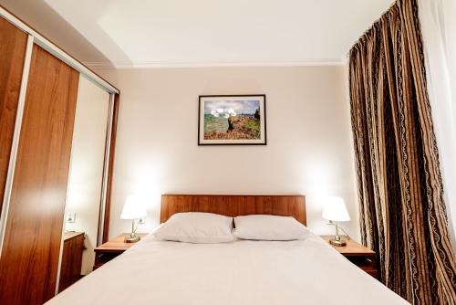 a bedroom with a bed and two lamps on tables at Chagala Hotel Aksai in Aksay