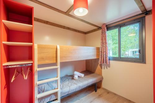 a bedroom with a bunk bed and a window at Camping du Château Vert in Hondainville