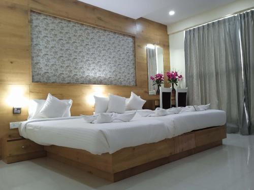 een groot bed met witte kussens in een slaapkamer bij Tranquil-Homes Ishwerya Suites in Bangalore