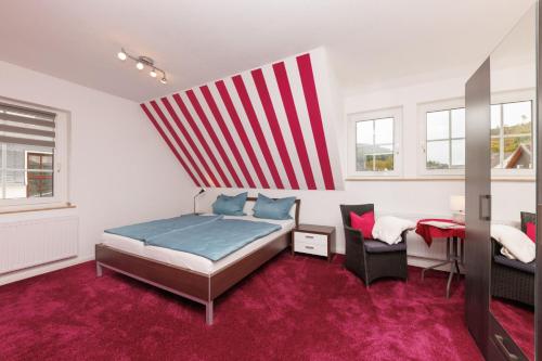 een slaapkamer met een bed en een rode en witte streepmuur bij Ferienwohnung Zum Schieferpfad in Bad Berleburg