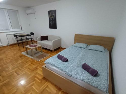 una camera da letto con un letto con cuscini viola e una sedia di Apartman Ana a Žarkovo