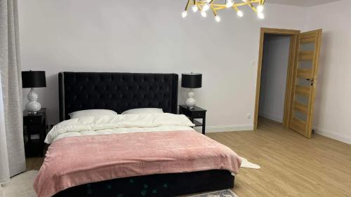 a bedroom with a large bed with a black headboard at Apartament Złoty 4 in Zblewo