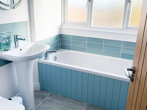 a bathroom with a bath tub and a sink at Sea Fern Luxury Cottage Fylingthorpe in Fylingthorpe