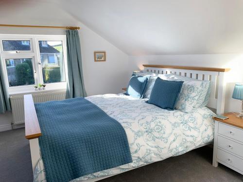 a bedroom with a bed with blue pillows and a window at Sea Fern Luxury Cottage Fylingthorpe in Fylingthorpe